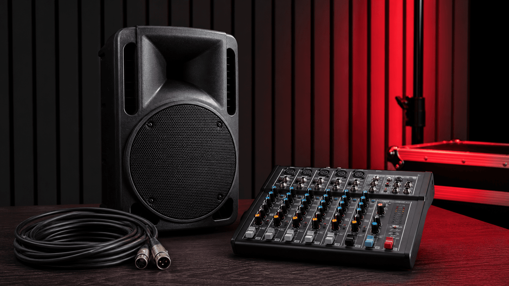 PA speaker, audio mixer, and XLR cable on a dark studio table